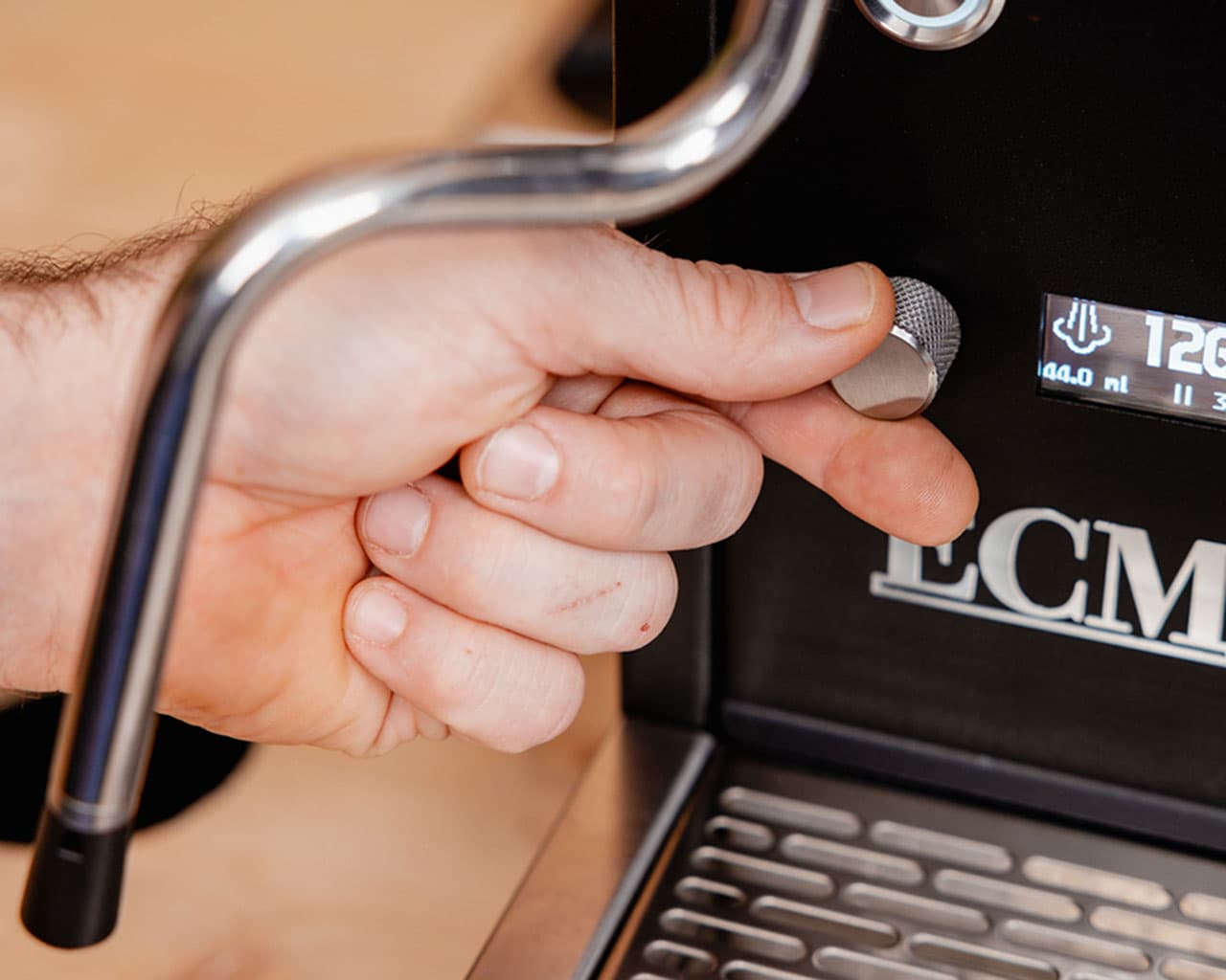 Hand dreht Metallregler an ECM Estetika Espressomaschine, Nahaufnahme von Bedienelement und Display