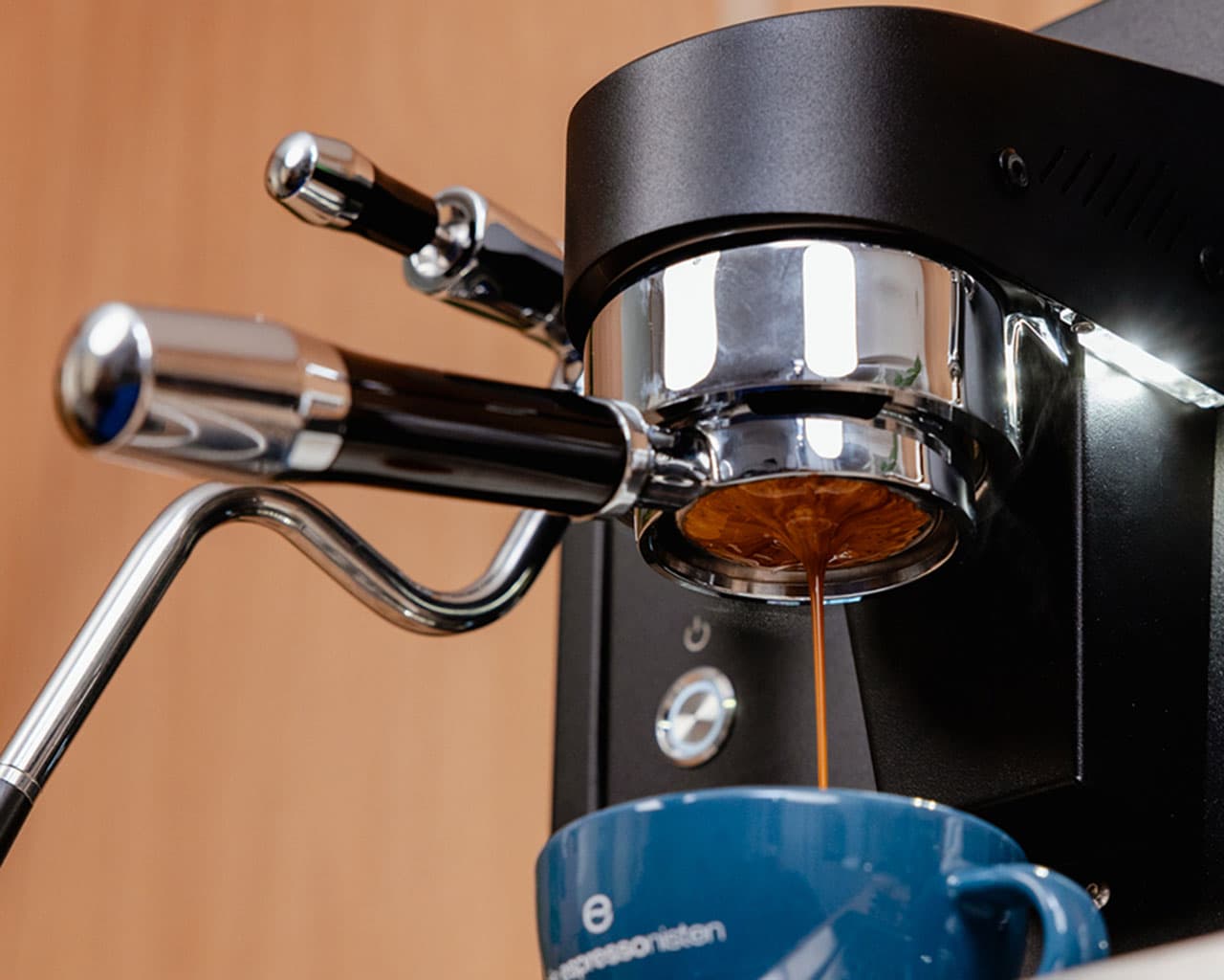 ECM Estetika Espressomaschine beim Auslaufen von Espresso in eine blaue Tasse, Portafilter und Dampflanze sichtbar