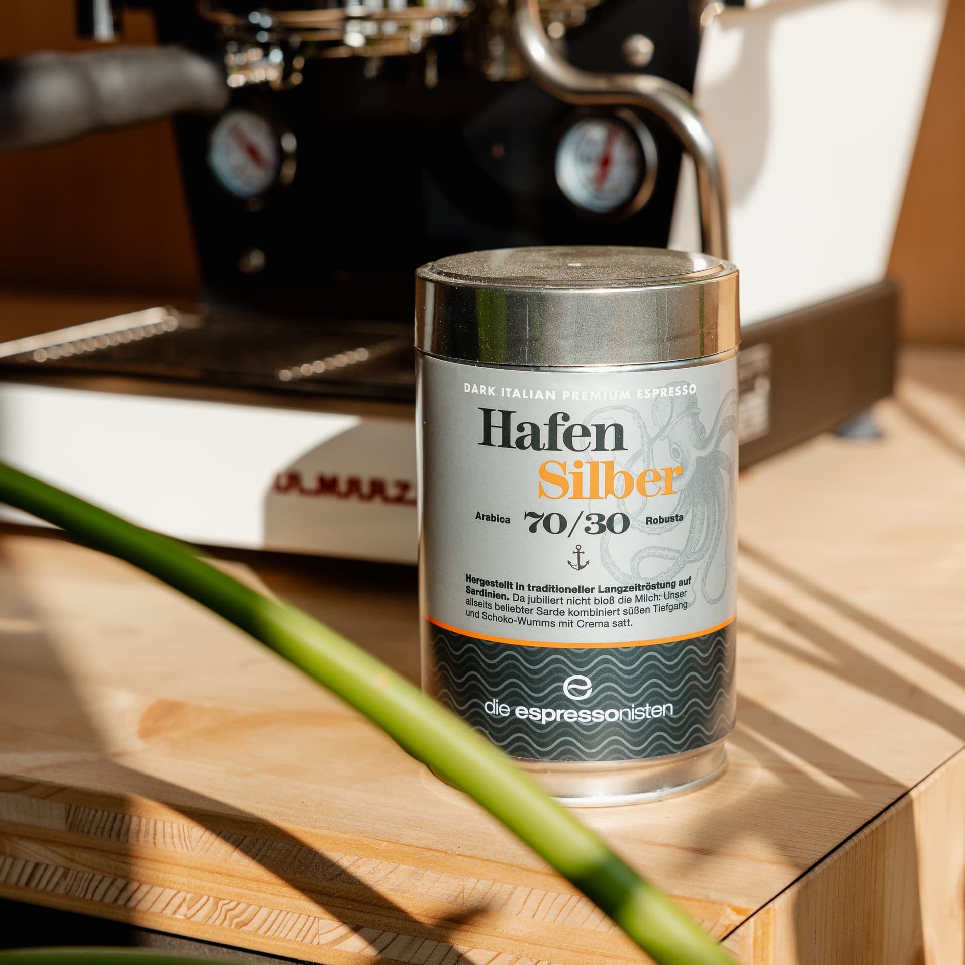Silberne Kaffeebüchse „Hafen Silber“ im Vordergrund, Espressomaschine und Tamper unscharf im Hintergrund