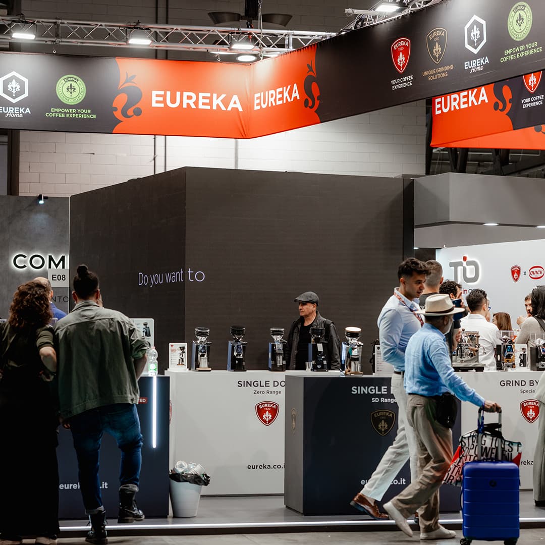 Messestand von Eureka auf Host Milano mit Kaffeevollautomaten, Mühlen und Besuchern am Ausstellungsstand