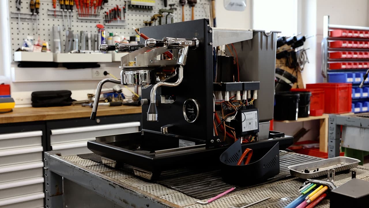 Aufgeschraubte ECM Estetika Espressomaschine in Werkstatt mit sichtbaren Brühgruppen, Leitungen und Werkzeug auf Arbeitstisch
