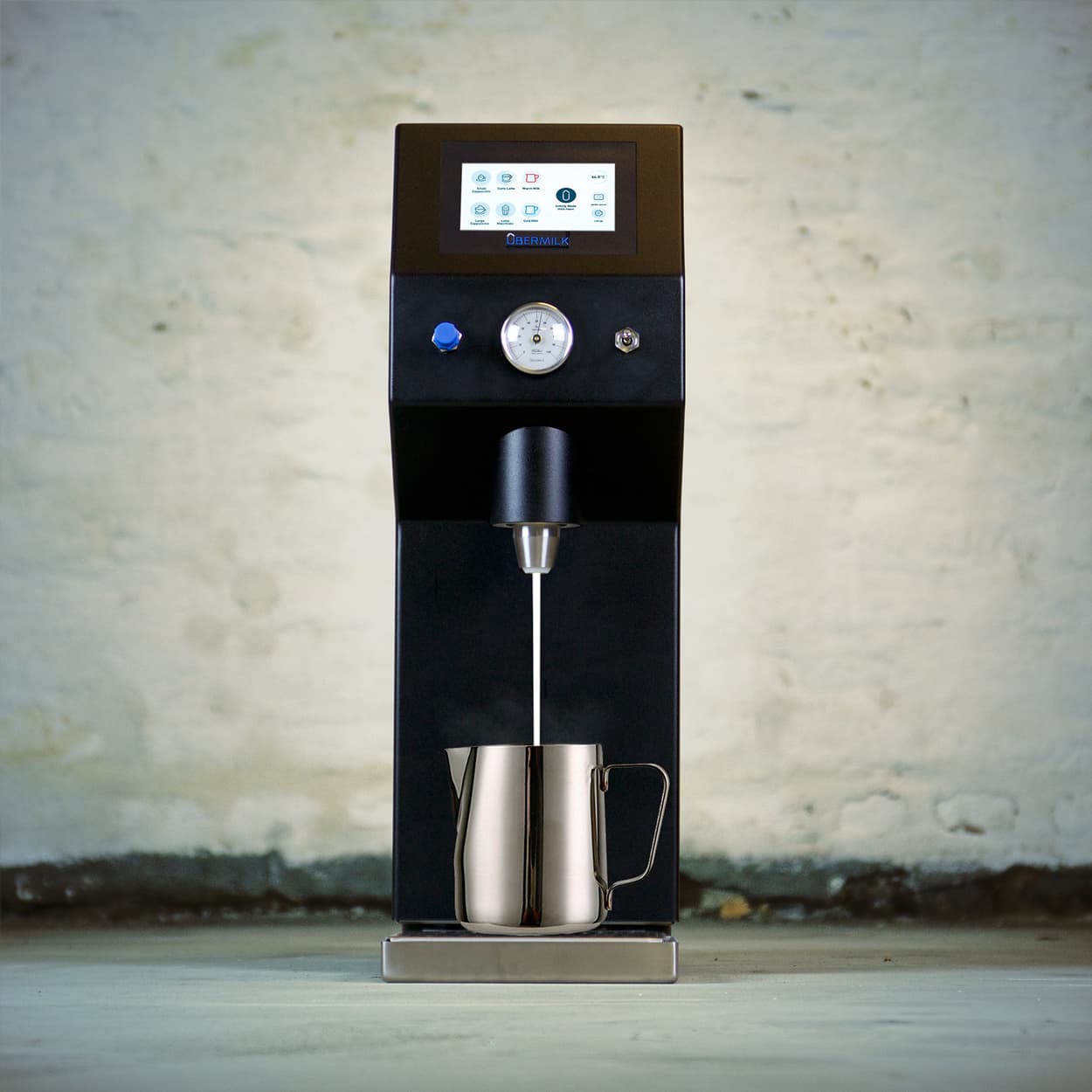 Schwarze Übermilk Milchaufschäumer-Maschine mit digitalem Display und Edelstahl-Milchkännchen, Milchstrahl in Kännchen