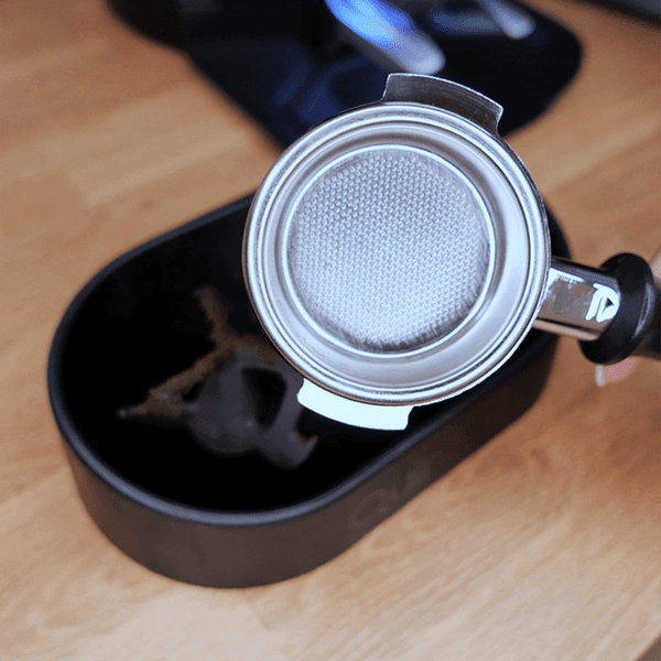 Portafilter mit feinmaschigem Sieb über Auffangbehälter auf Holzplatte, Kaffeerezepte/QuinSpin Schritt 4