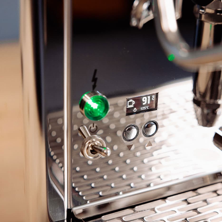Nahaufnahme der glänzenden ECM Technika Siebträgermaschine mit Display (91°C), Tasten und grünem Betriebslicht