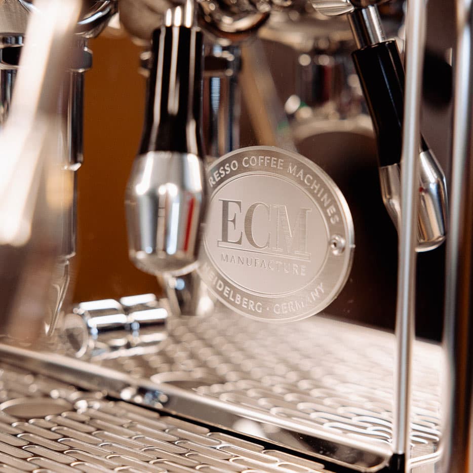 Nahaufnahme der glänzenden ECM Technika Espressomaschine mit Logo, Siebträger und Dampflanze, Edelstahloberfläche